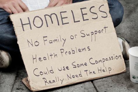 A person holding a cardboard homeless sign